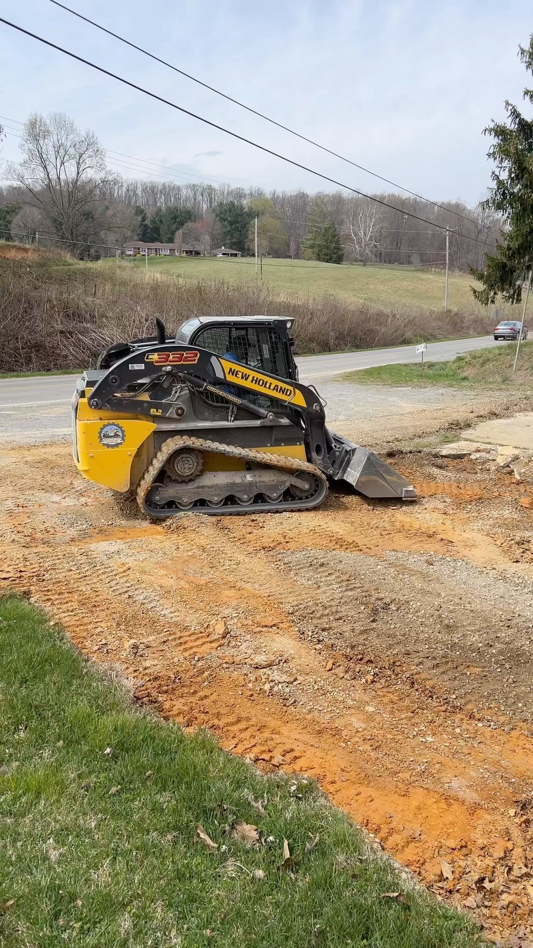 Yellow and black skid steer on dirt, working near a road.