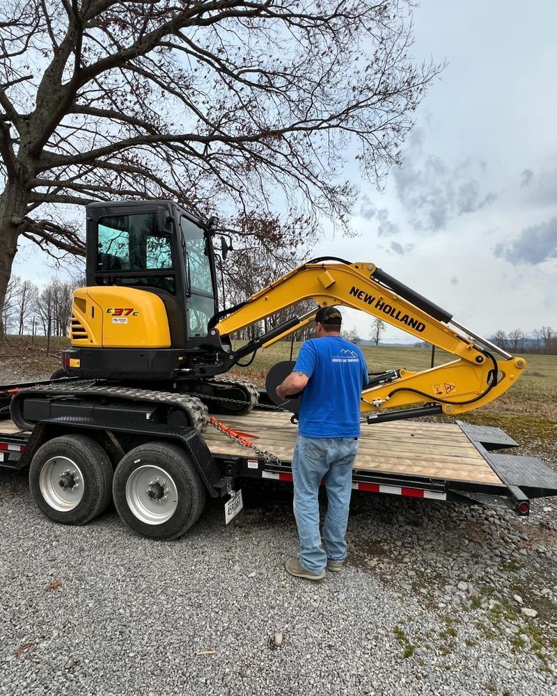 Man on trailer with yellow New Holland excavator.