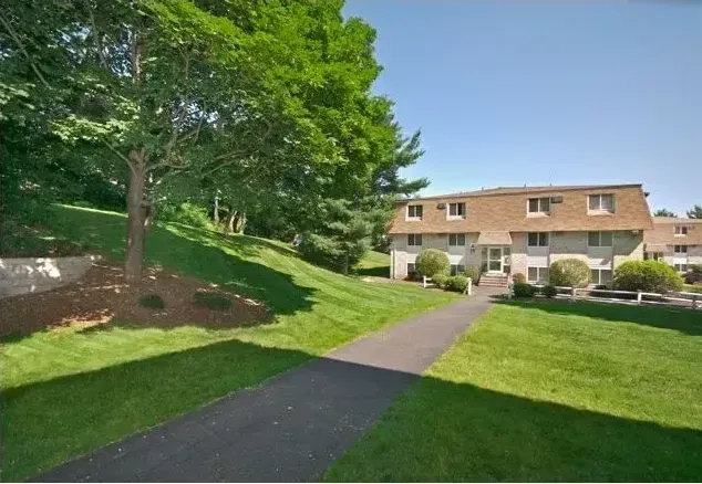 A house with a lush green lawn and trees in front of it