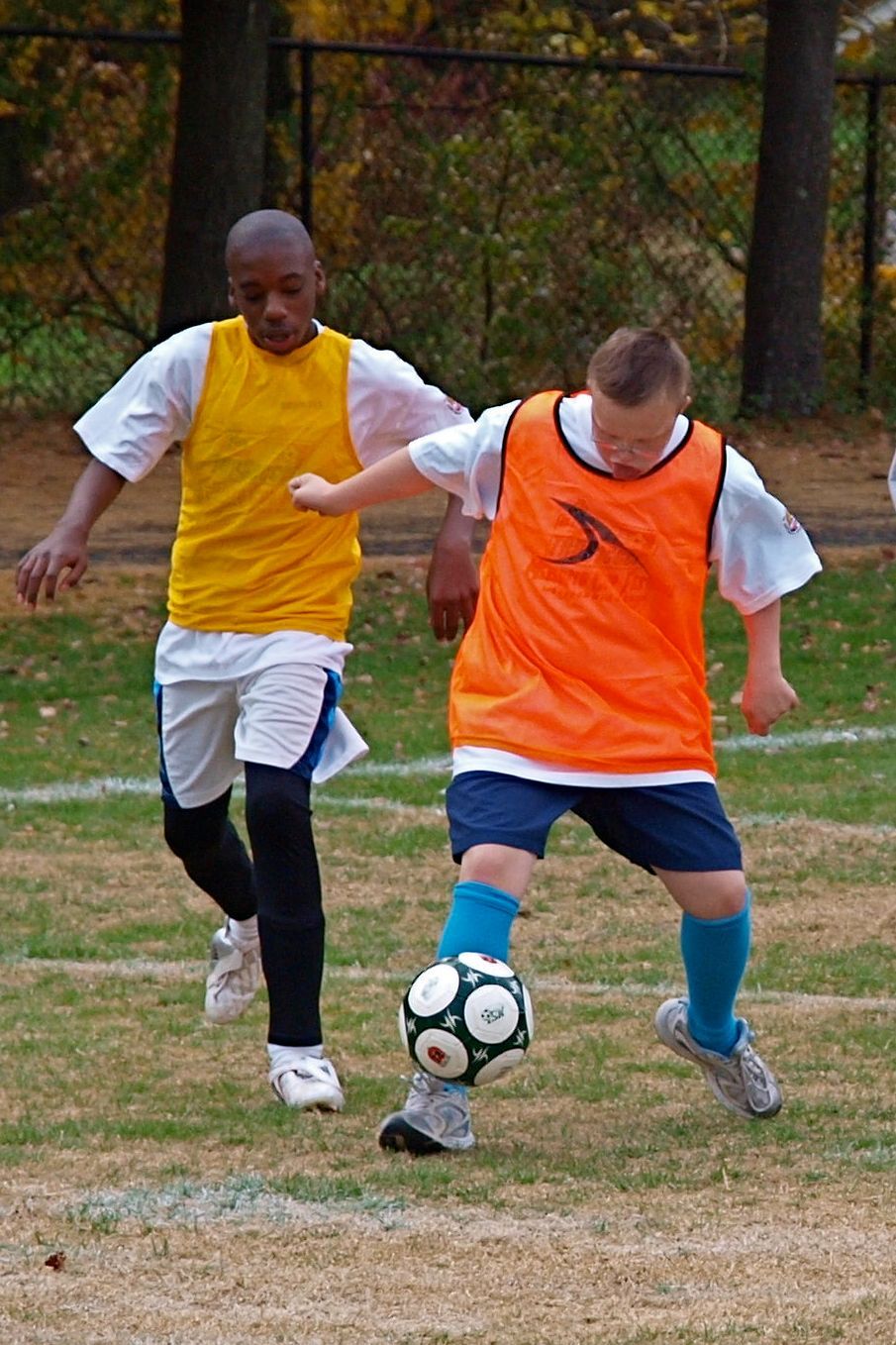 Youth MSI soccer athletes wearing orange and yellow training vests work on drills together during a practice session.
