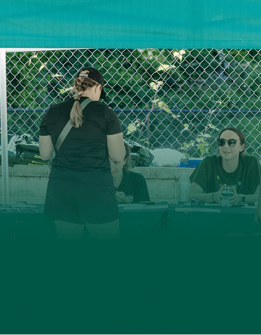 A parent registering a team at a check-in table beside the field