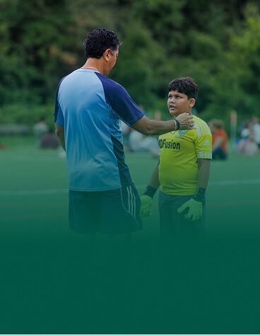 A coach giving instructions to a young player on the sideline