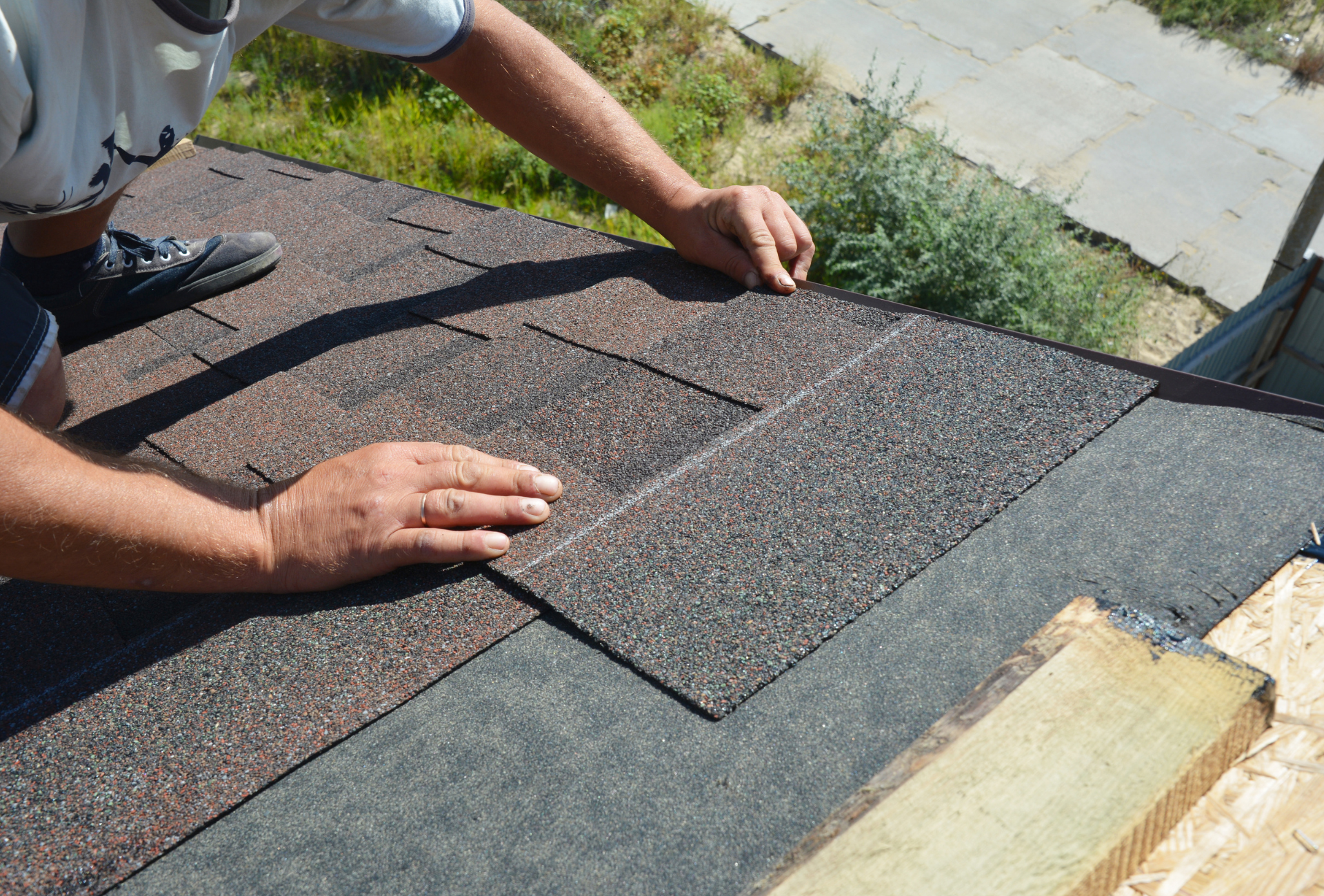 A man is laying shingles on a roof.