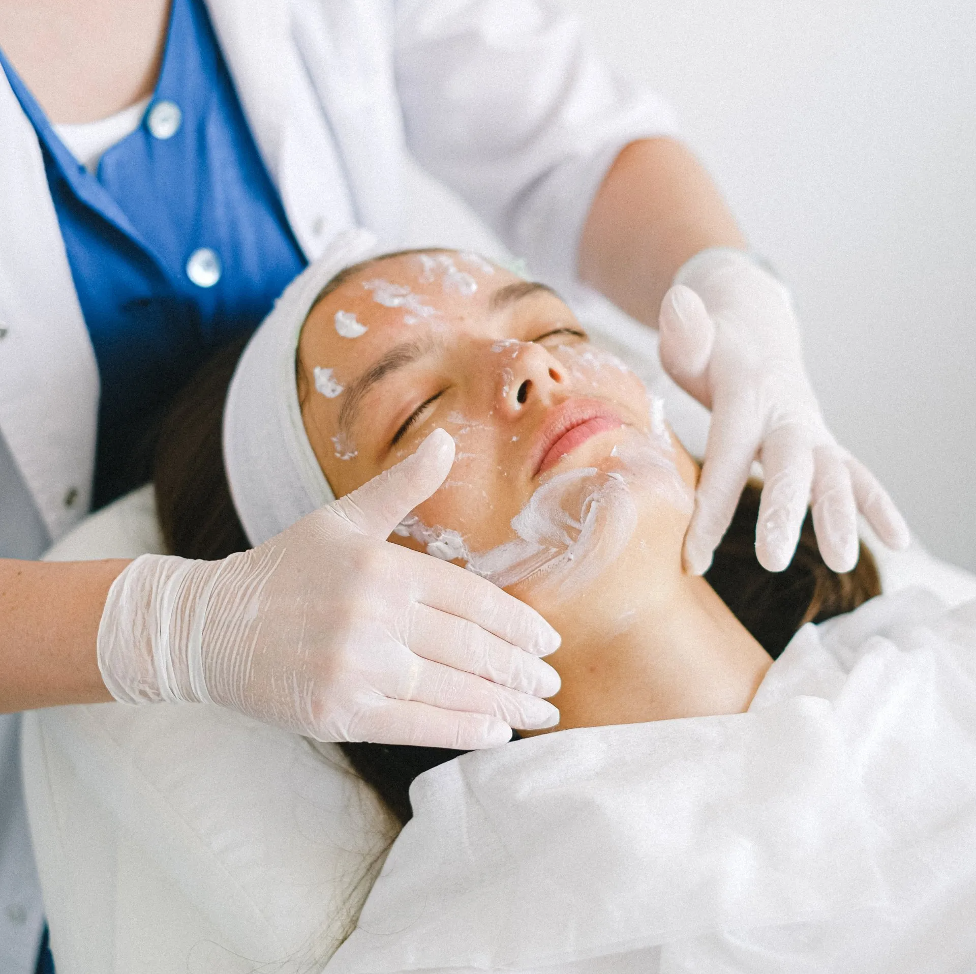 woman having a face cream applied laying on a table