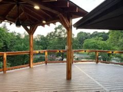 Wooden deck with gazebo overlooking trees.