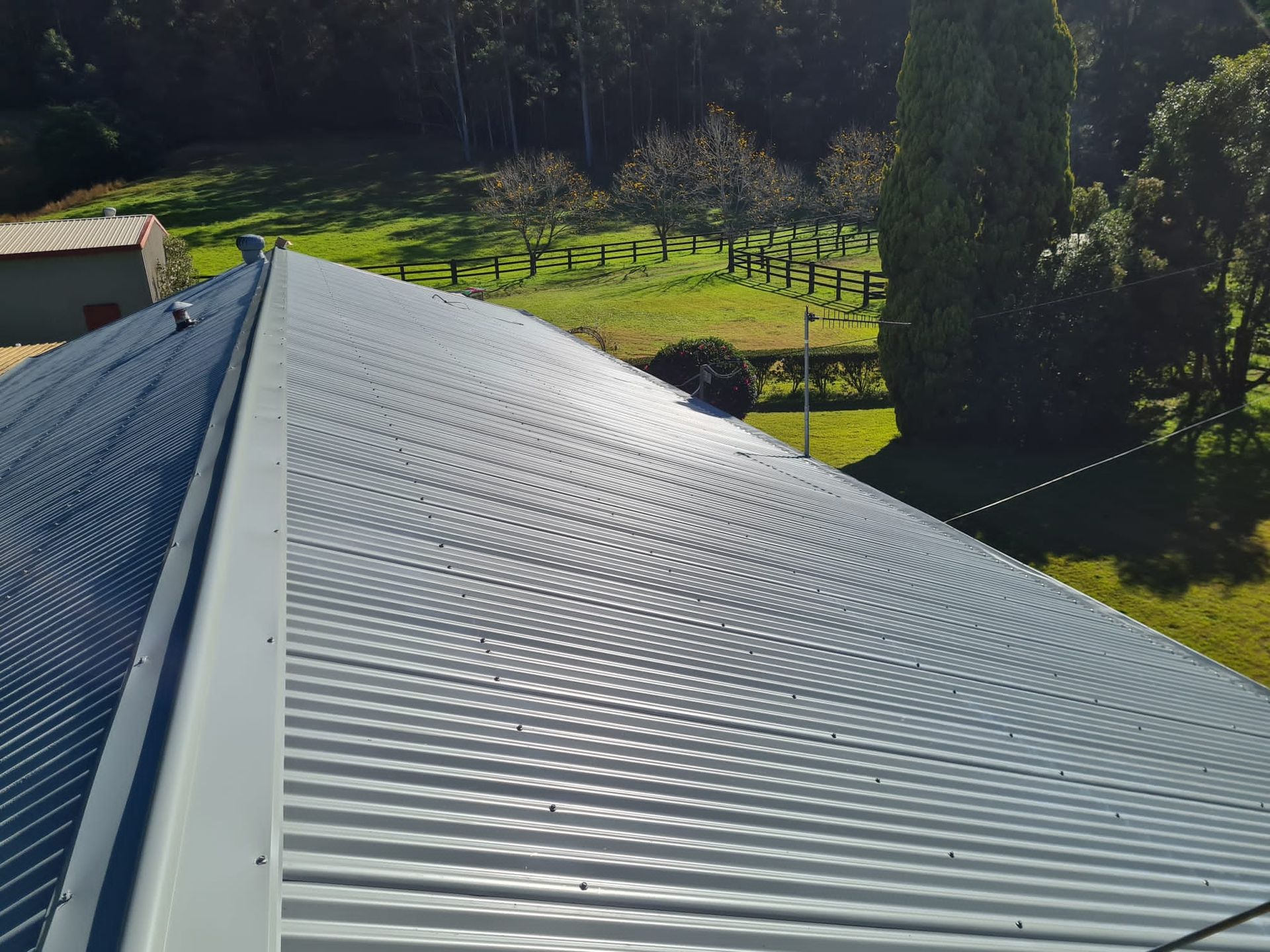 A view from a high vantage point looking down at a corrugated metal roof, with a rural landscape in the background.