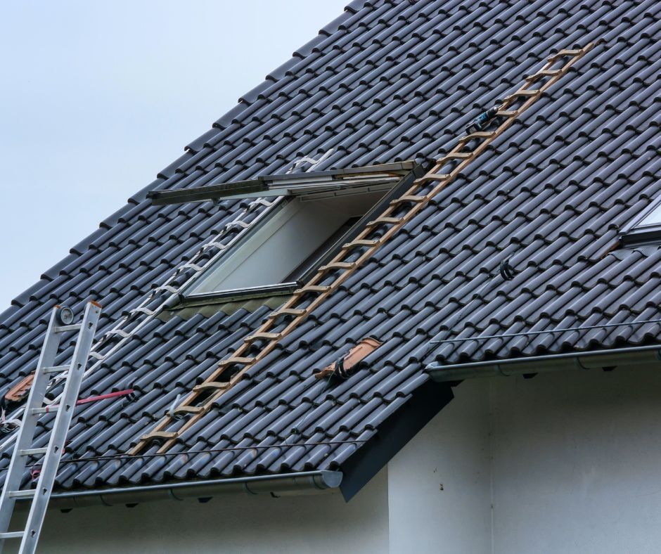 Two wooden roof ladders are positioned on a tiled, steeply pitched roof near an open skylight window.