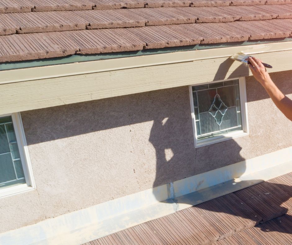 A professional roofer painting a roofing fascia board.