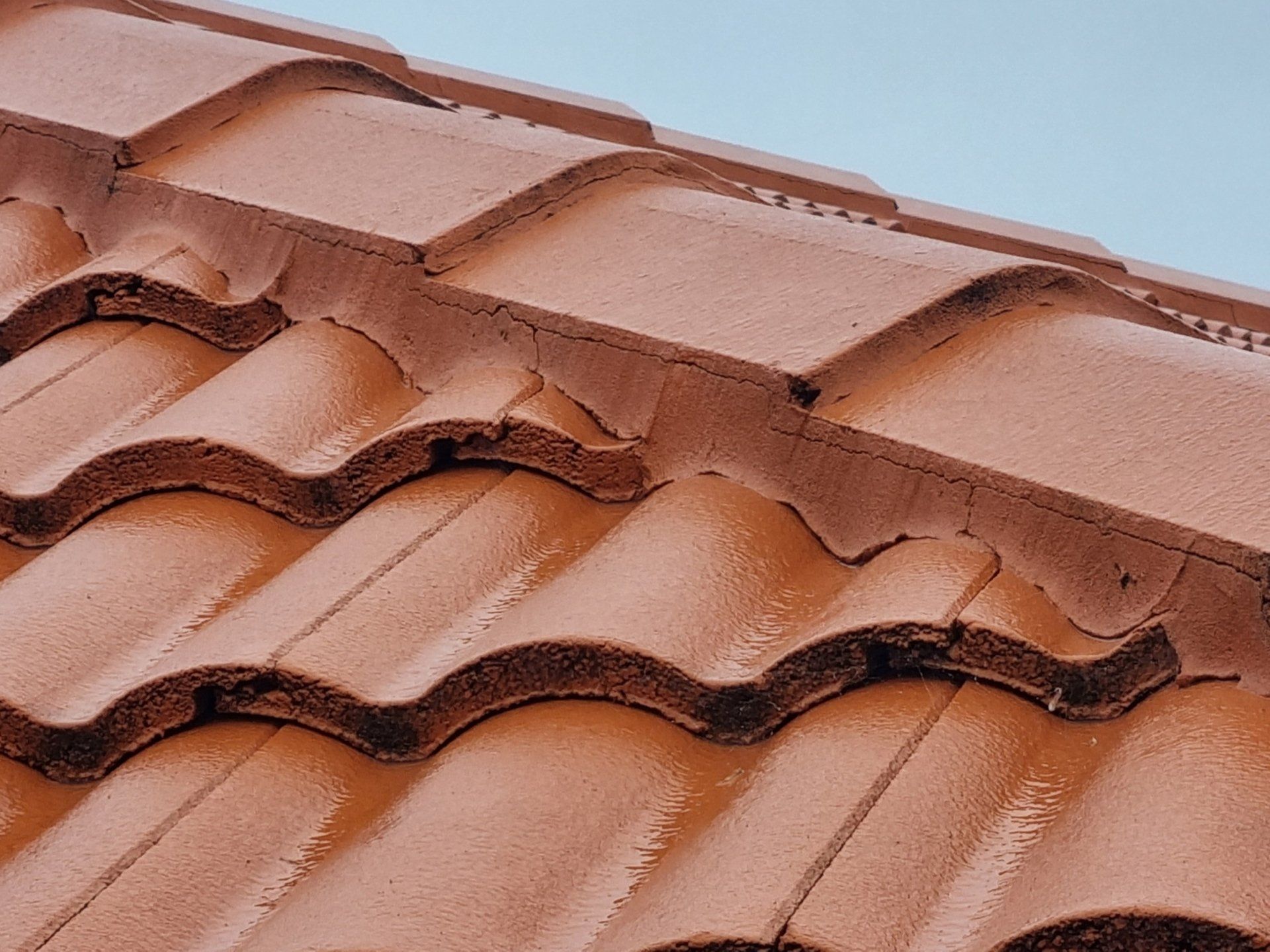 Close-up of reddish-brown concrete roof tiles showing mortar bedding along the ridge line.