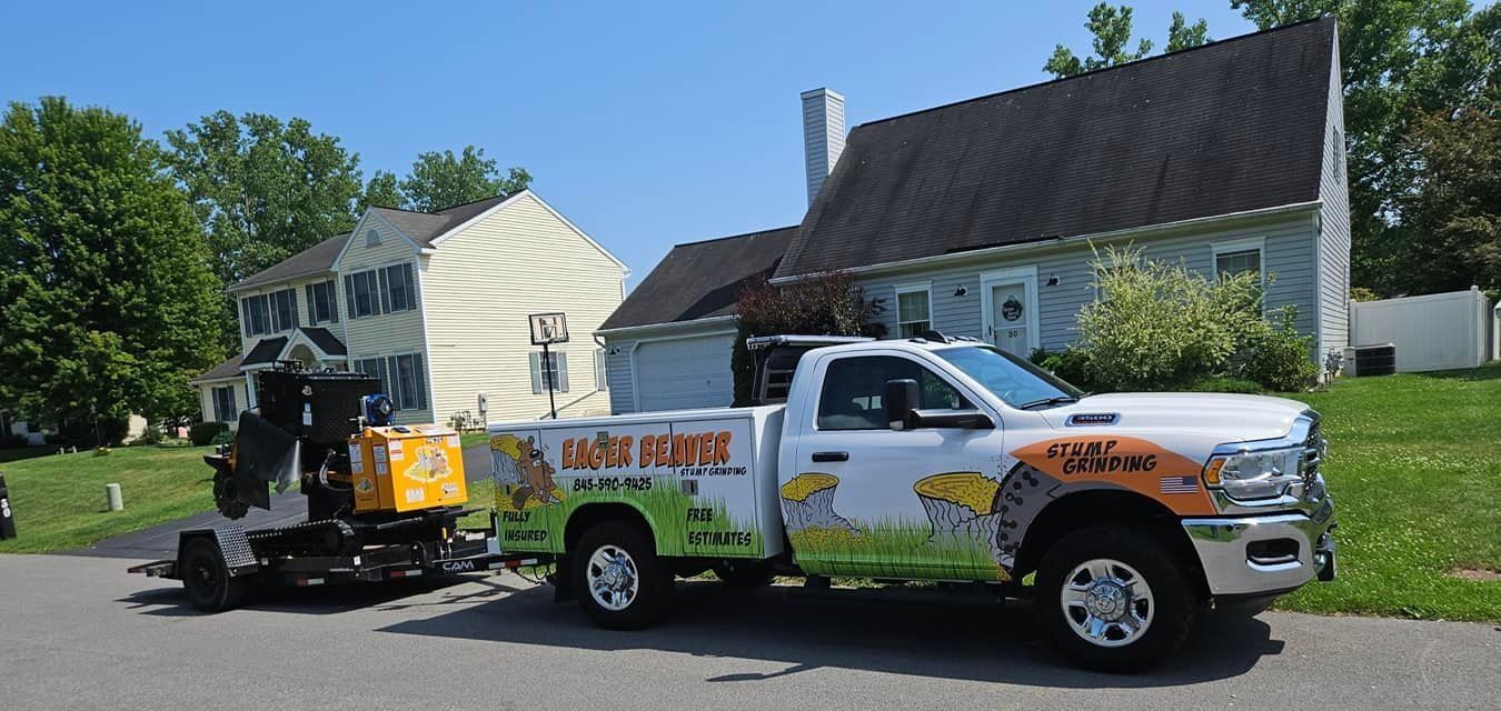 White service truck with logo parked on a sunny suburban street beside a yellow utility machine and houses