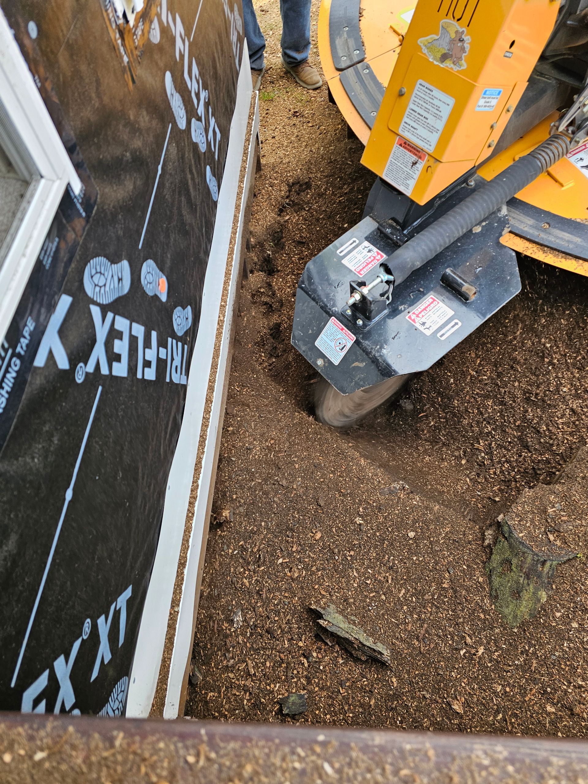 Top-down view of a yellow forklift beside a wall and a gravel-filled trench with debris.