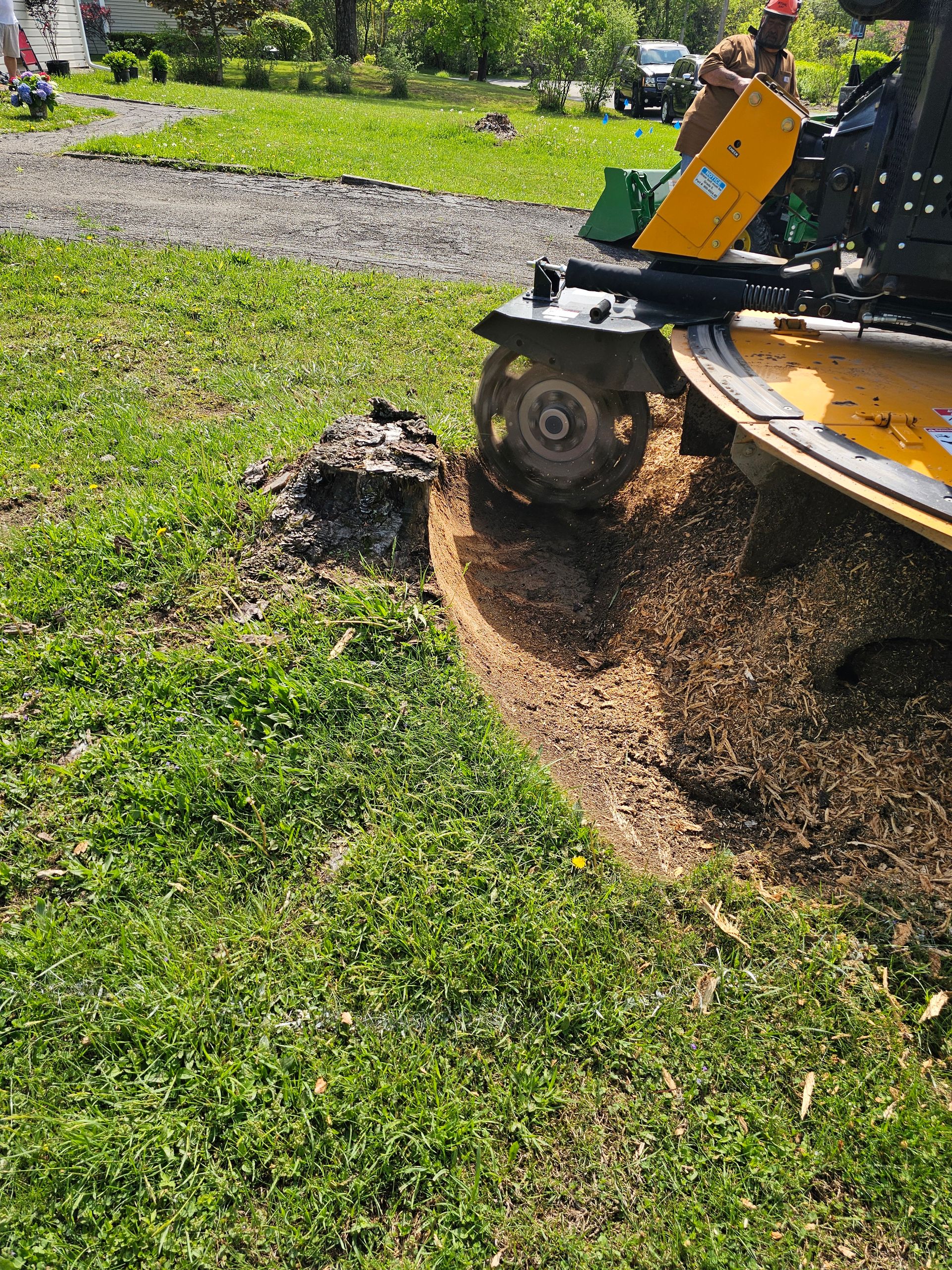 Small landscaping machine cutting a trench through grass beside a gravel path in a park
