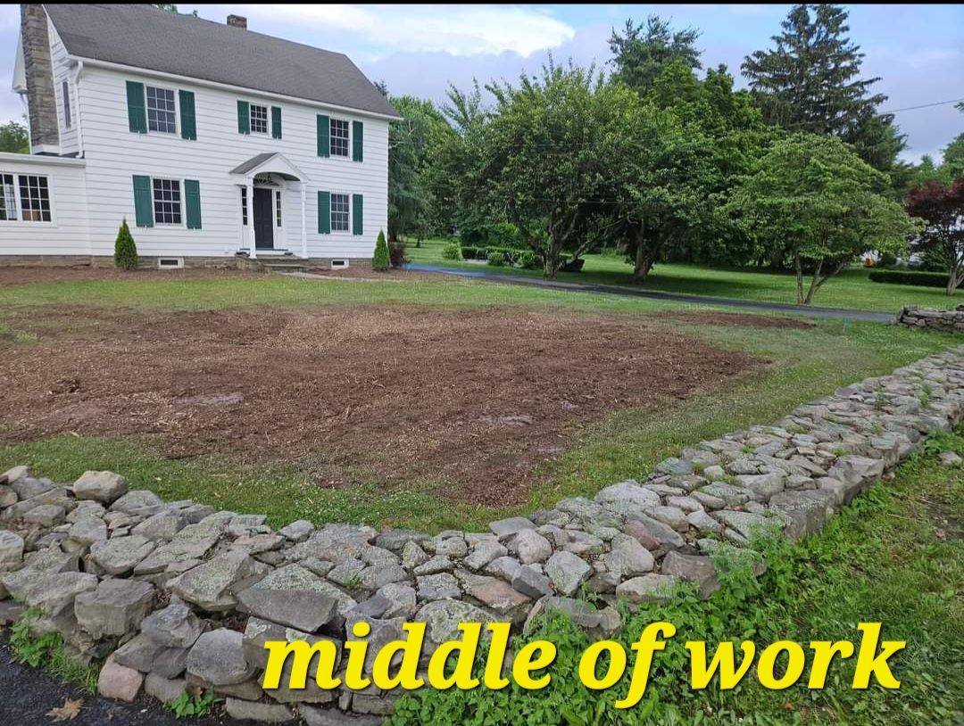 House with green shutters beside a freshly cleared yard and stone border, labeled “middle of work”