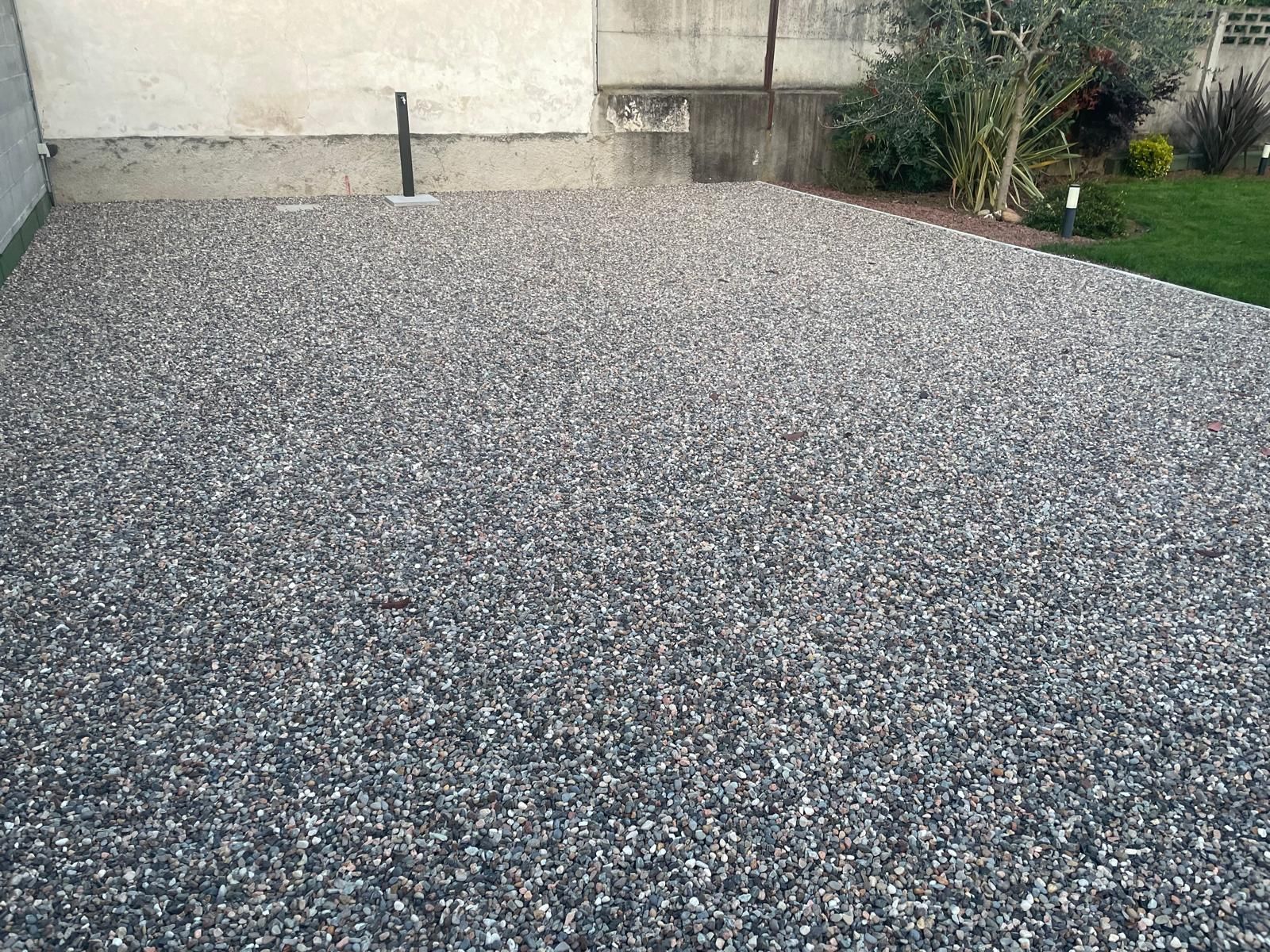 Vialetto ricoperto di ghiaia accanto al muro di cinta e al giardino di una casa.