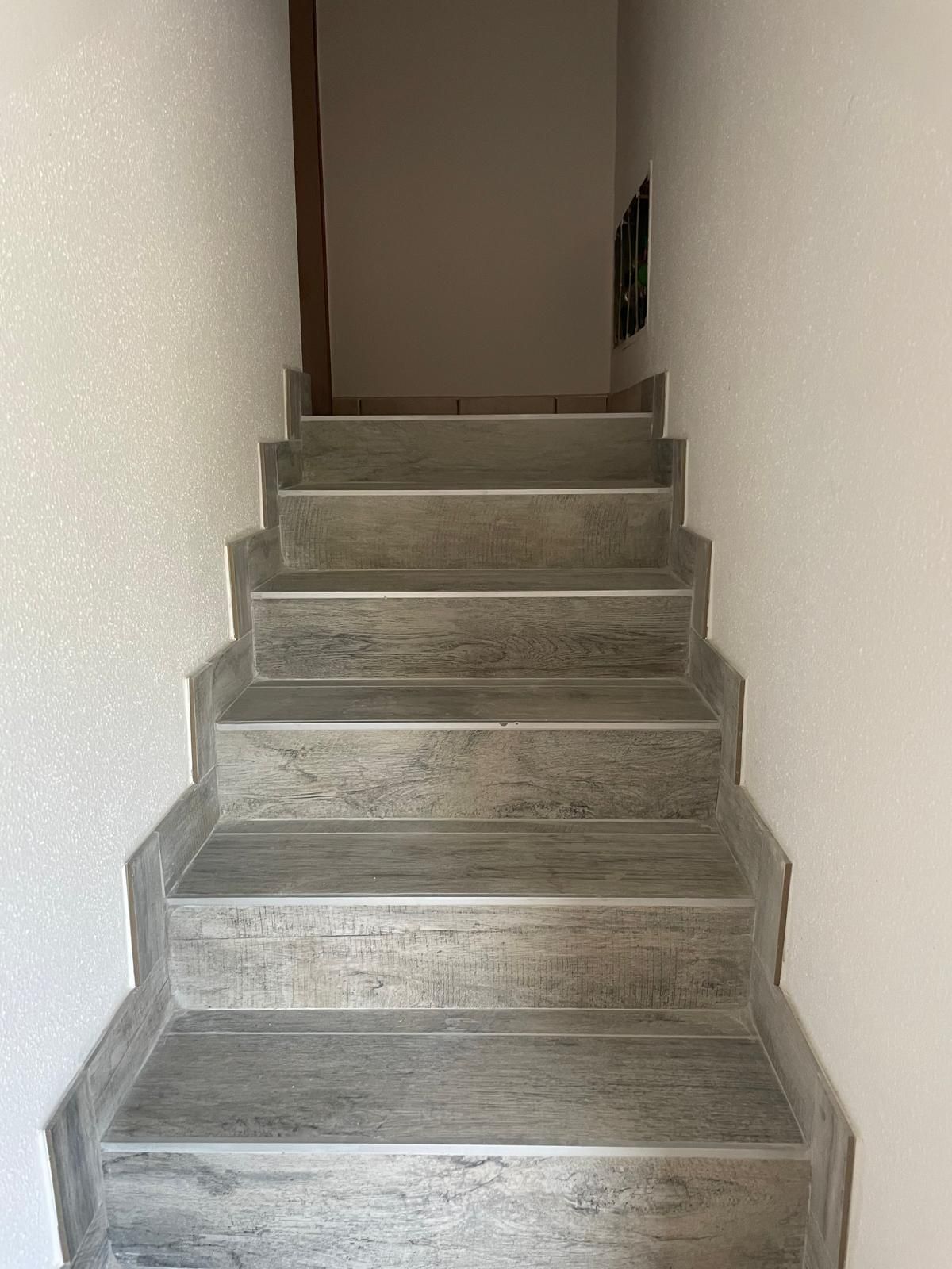 Scala interna stretta con gradini in cemento grigio e pareti bianche che conducono verso l'alto