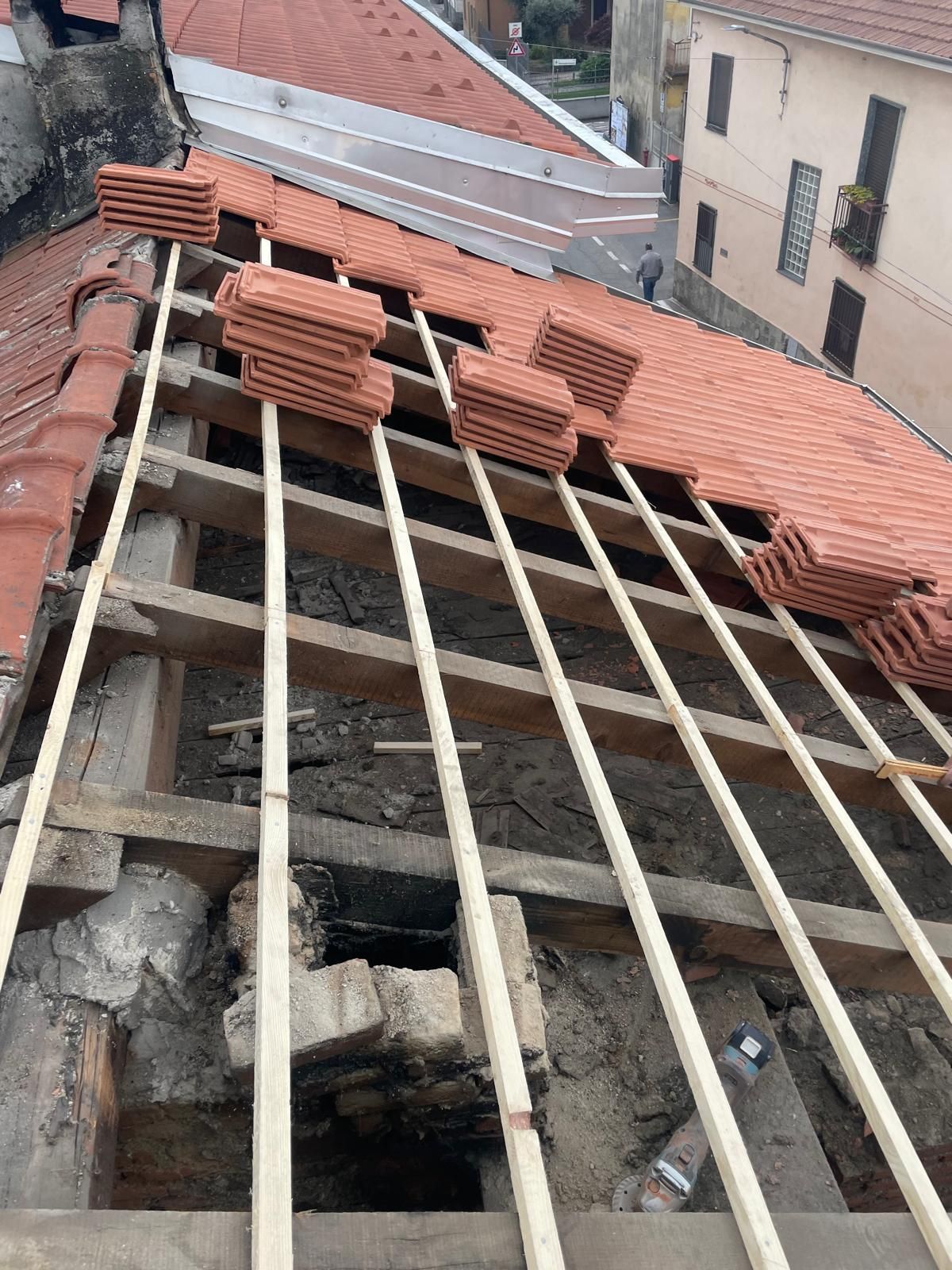 Edificio parzialmente coperto con travi a vista e tegole rosse sovrapposte, in fase di costruzione.