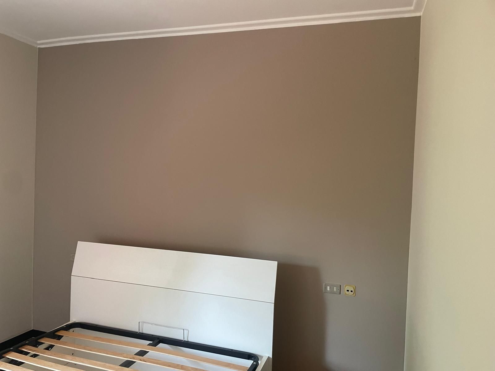Una struttura di letto appoggiata a una parete beige in una stanza vuota