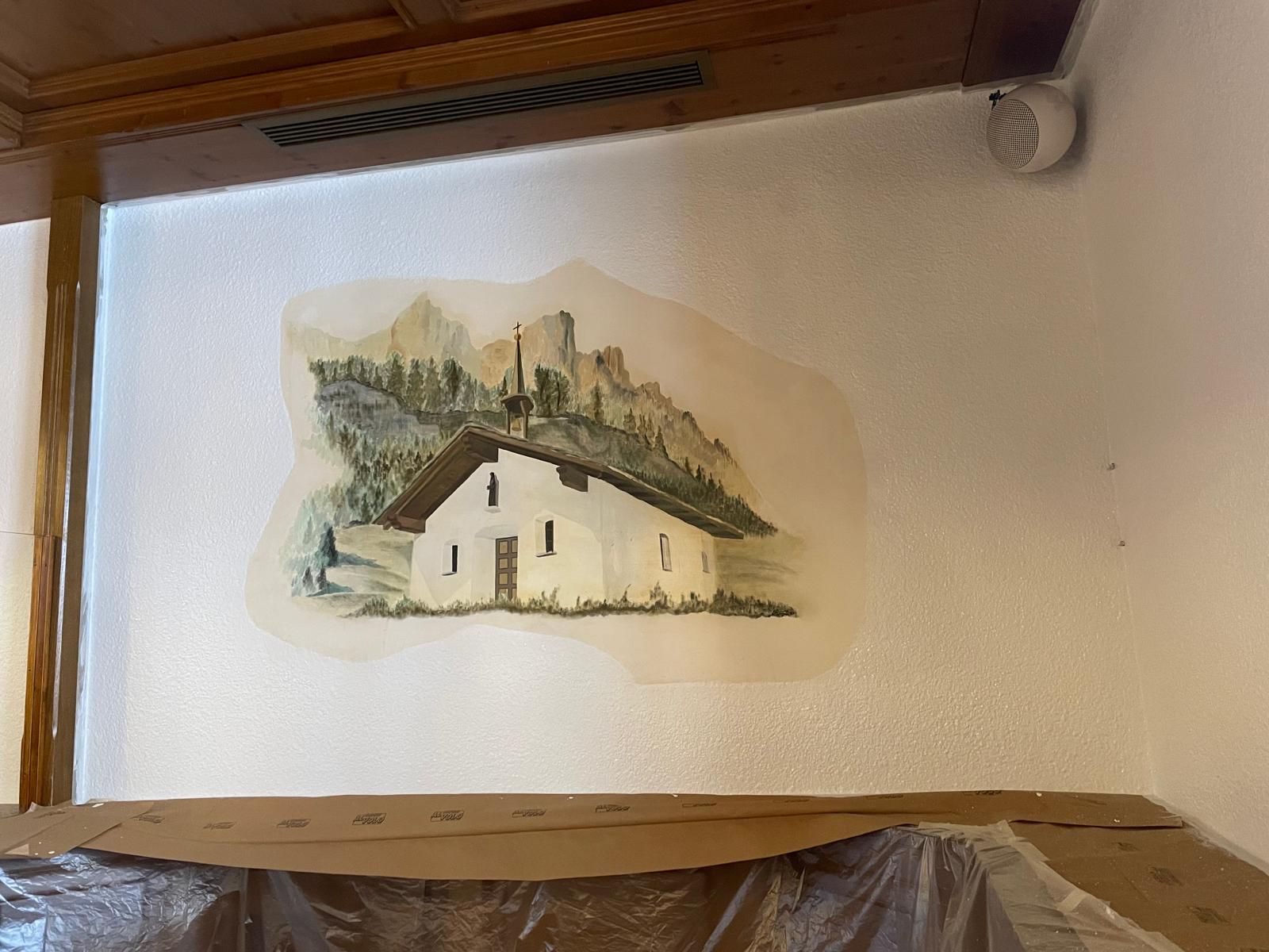 Adesivo murale raffigurante una piccola casa bianca con un paesaggio e un edificio simile a una chiesa sullo sfondo.