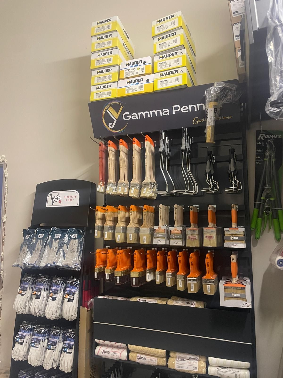Espositore per attrezzatura da pesca con canne da pesca Penn, attrezzi con manico arancione e accessori su scaffali neri.