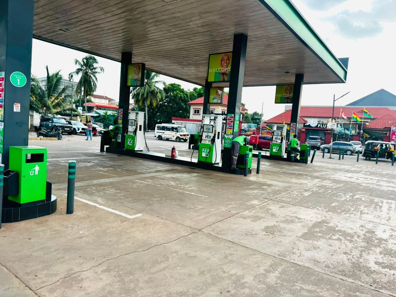 Modern gas station with green-and-white canopy and yellow building on a cloudy day