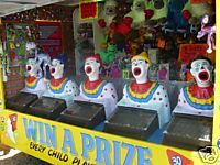Clown-themed carnival game with open-mouthed figures, likely for tossing balls into. 