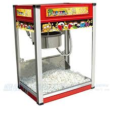 Red and silver popcorn machine filled with popcorn; a metal kettle is visible inside.