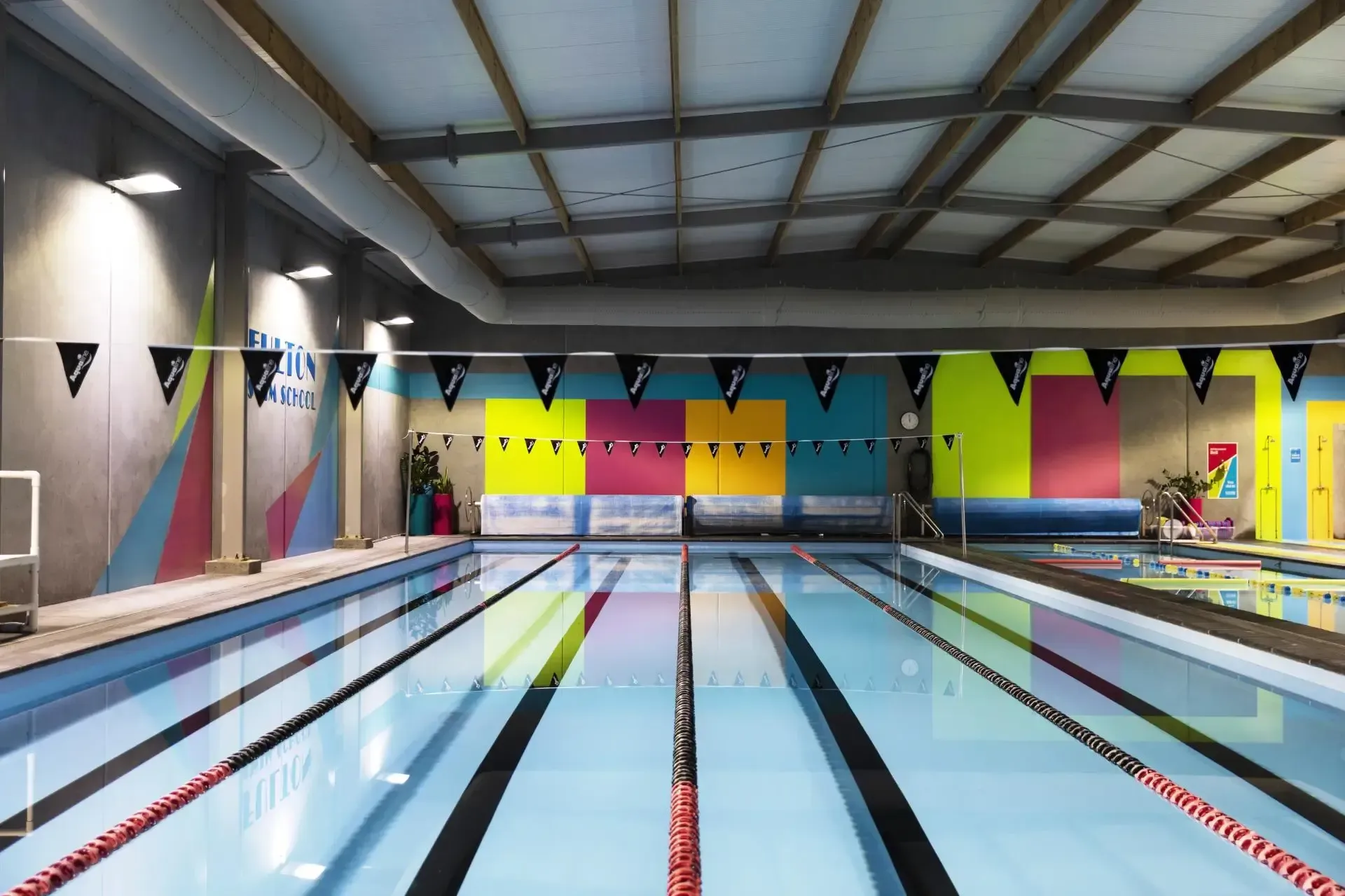 A large indoor swimming pool with colorful walls and flags