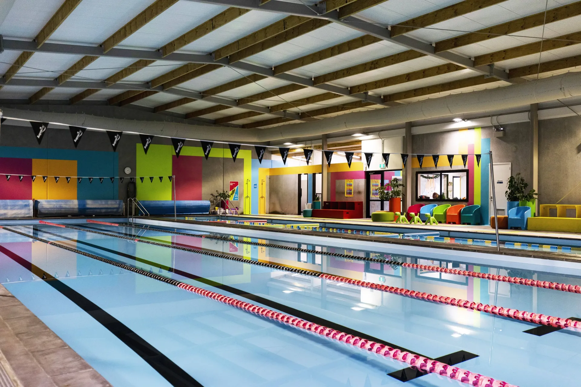 A large indoor swimming pool with colorful walls and a wooden ceiling.
