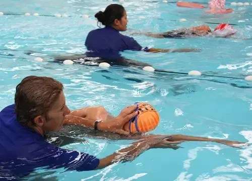 A group of people are swimming in a pool with a ball.