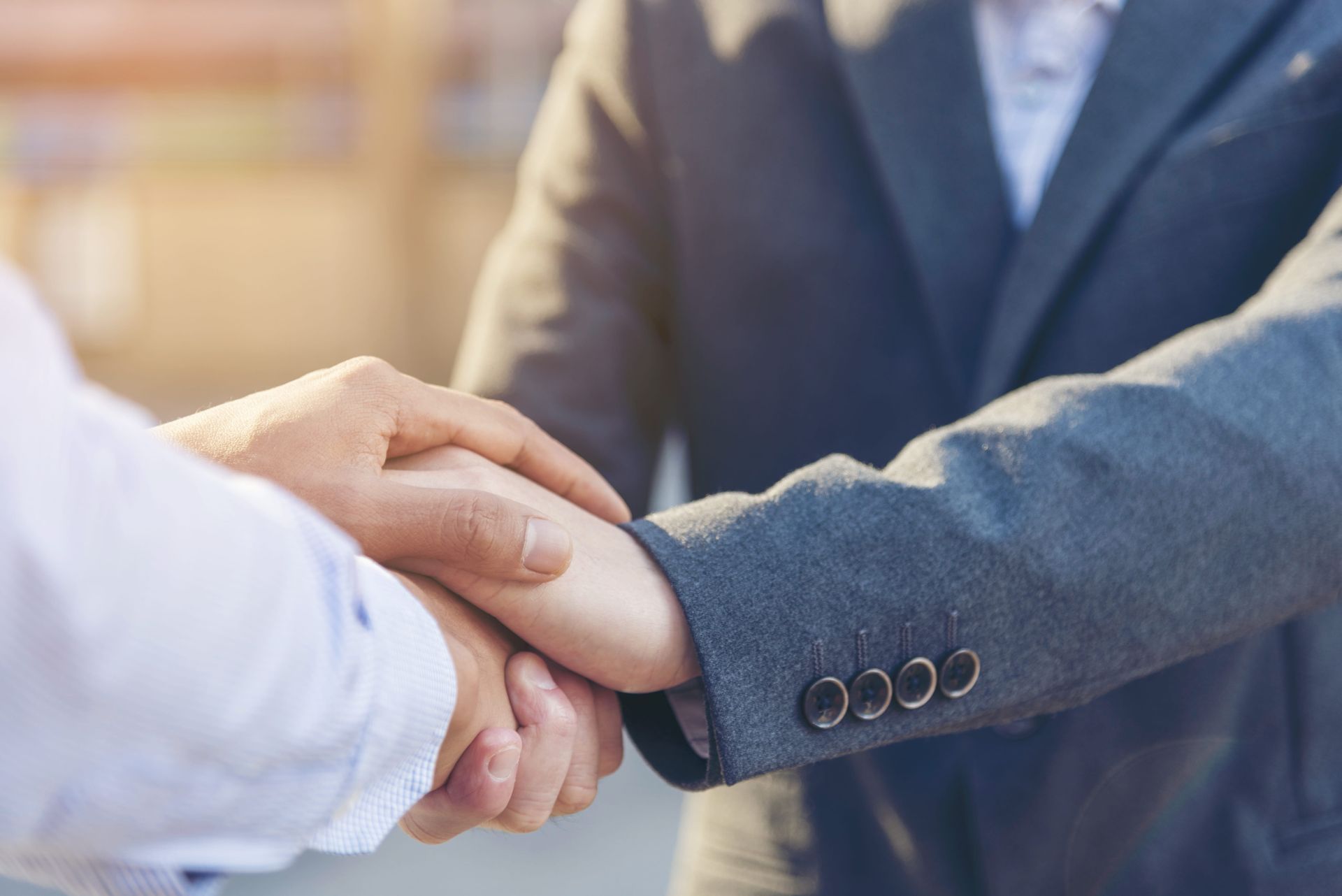A man in a suit is shaking hands with another man in a white shirt.