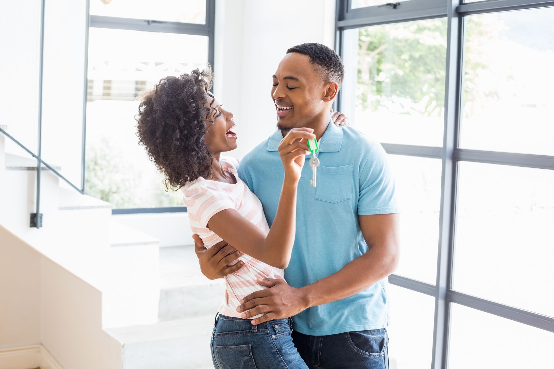 A man and a woman are dancing in their new home . the woman is holding a key.