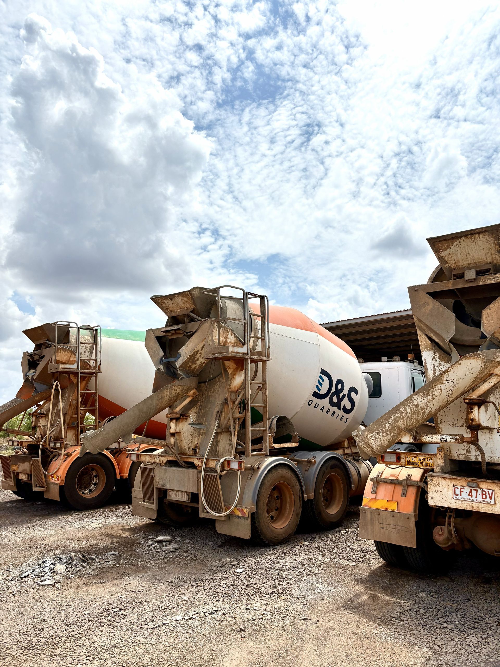 Three Concrete Mixer Trucks Parked on Gravel Under a Cloudy Sky — D&S Quarries in Lansdowne, NT