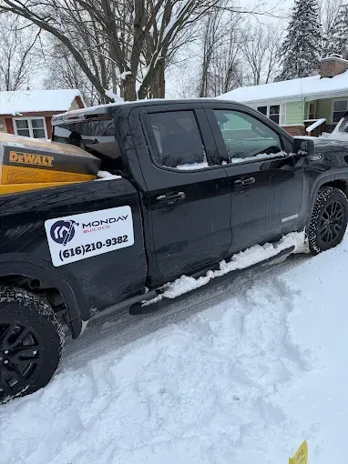 Black pickup truck parked in snowy driveway with a side logo and phone number decal