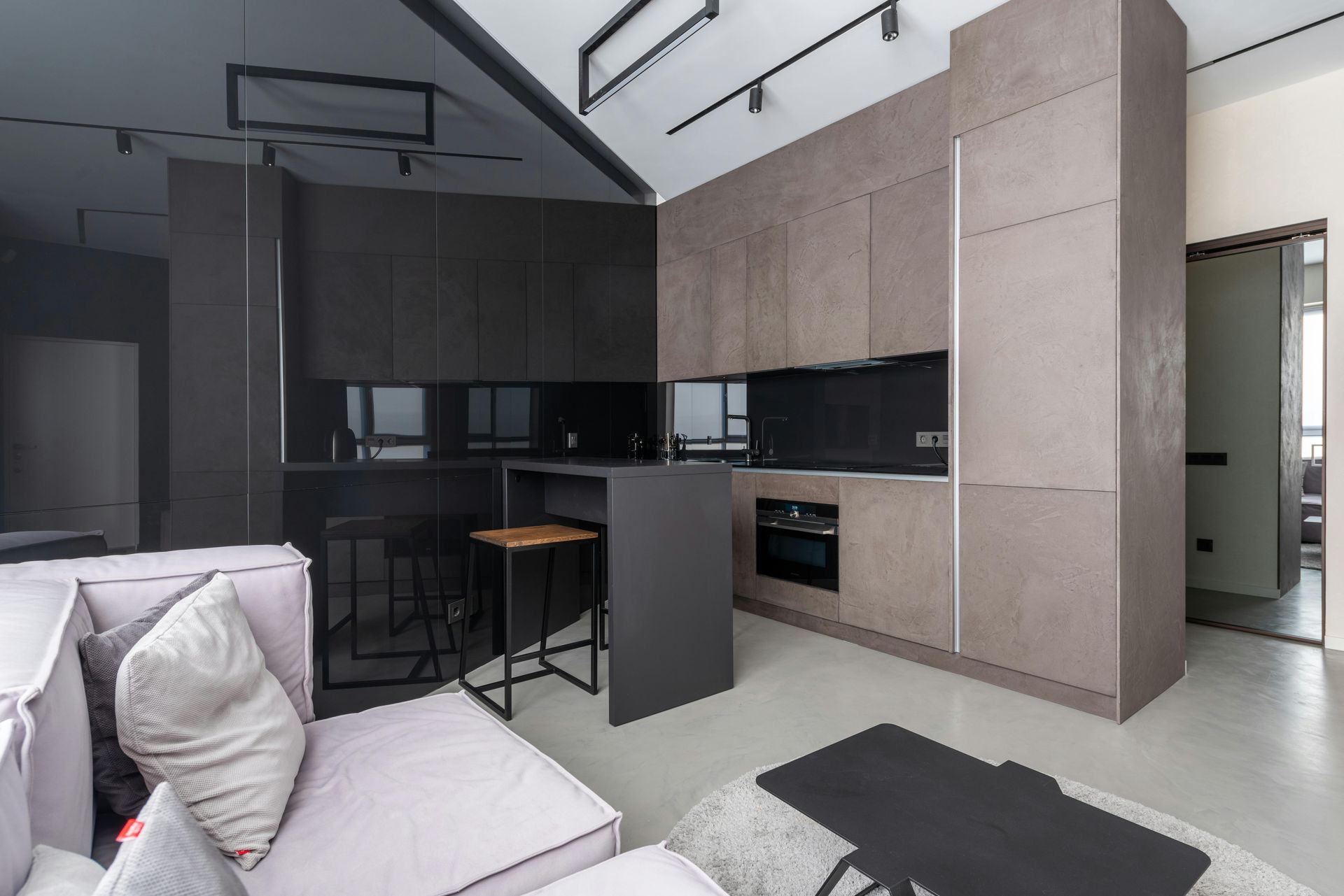 Modern loft apartment with gray sectional, sleek black-and-wood kitchen, and high vaulted ceiling