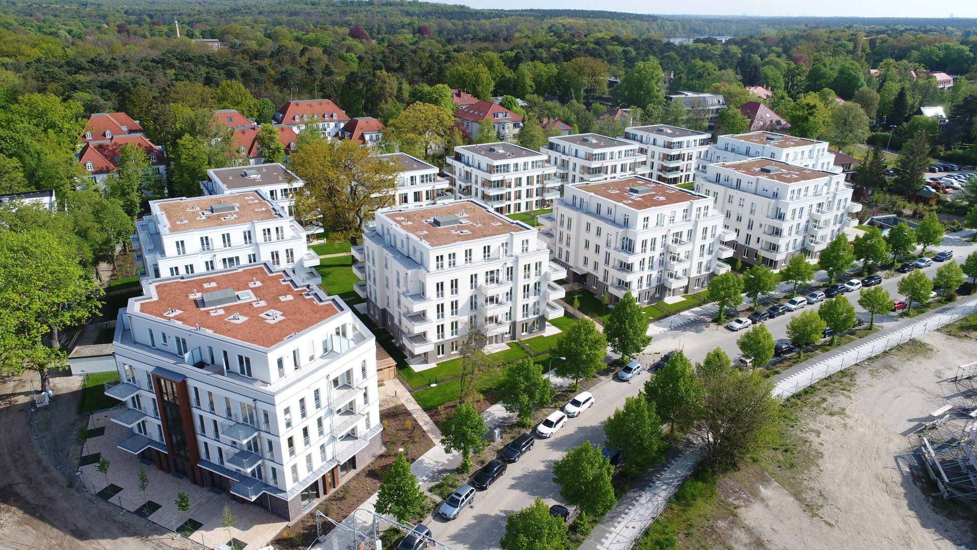 Luftaufnahme von weißen Wohnhäusern an einer von Bäumen gesäumten Straße in Babelsberg
