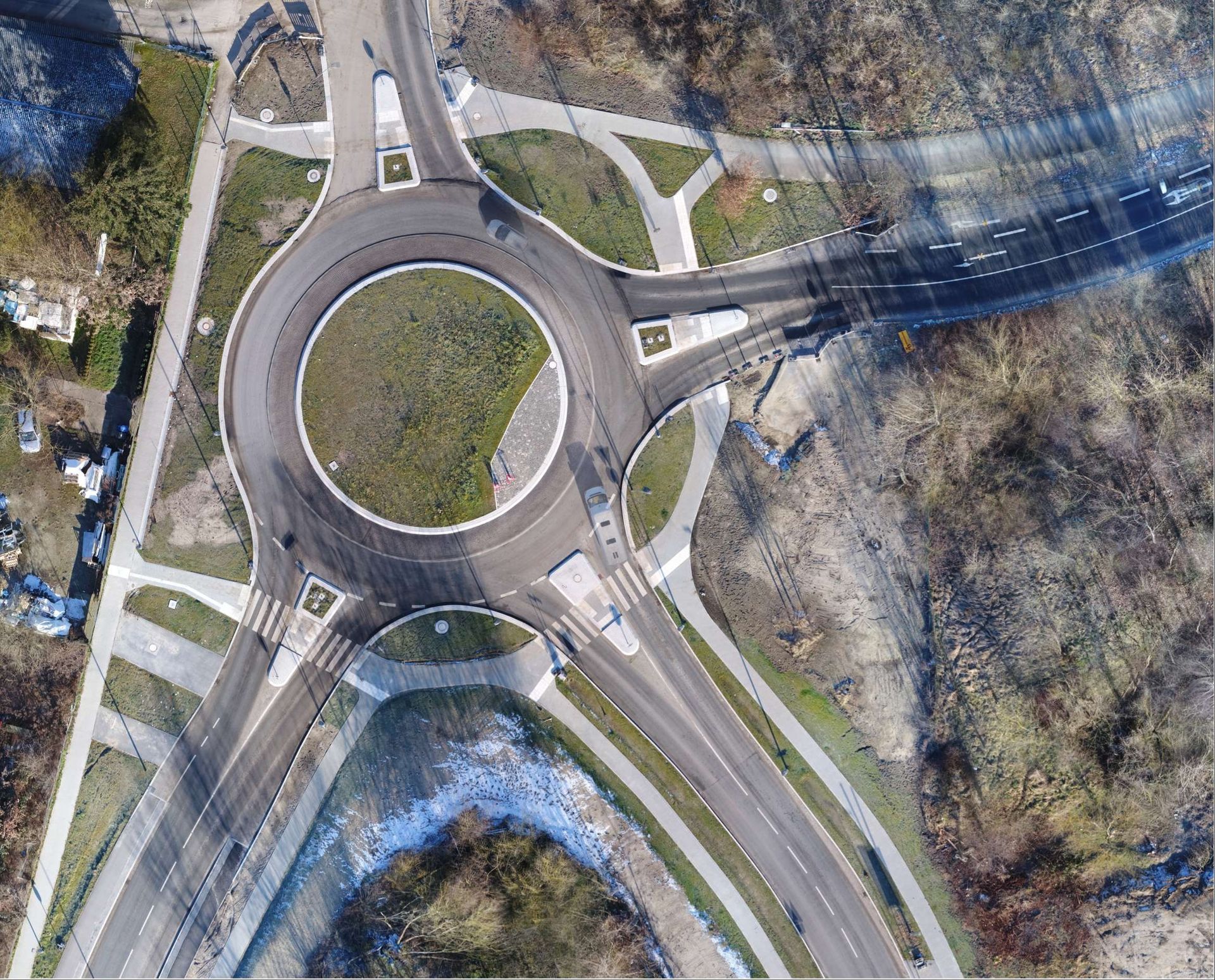Luftaufnahme eines Kreisverkehrs, von dem mehrere Straßen durch ein Waldgebiet abzweigen.