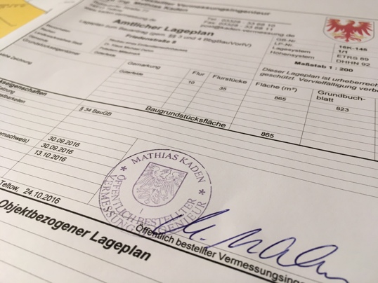 Nahaufnahme eines gesiegelten Amtlichen Lageplans mit handschriftlicher blauer Unterschrift