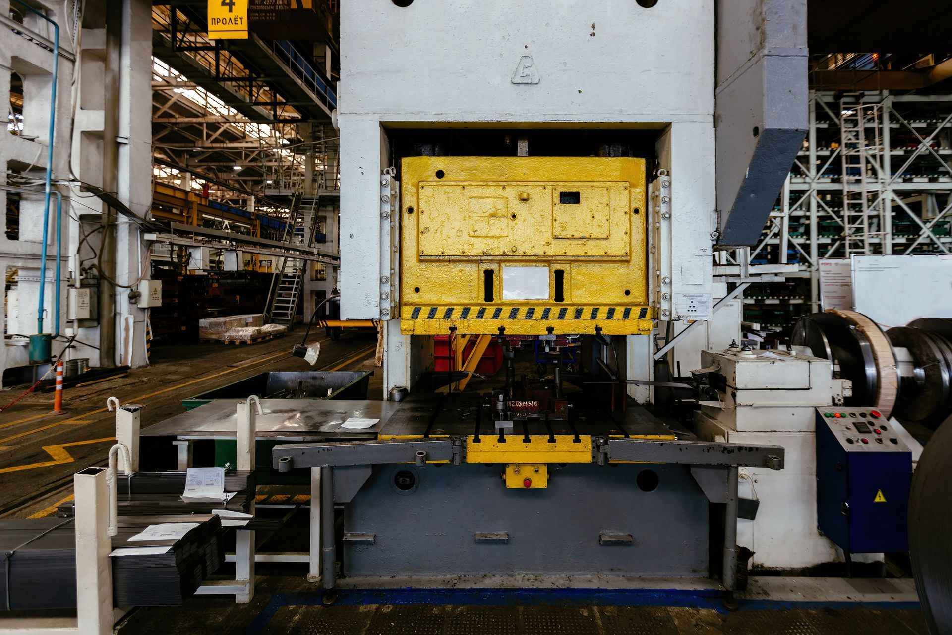 Large industrial press machine in a factory, yellow and gray colors.