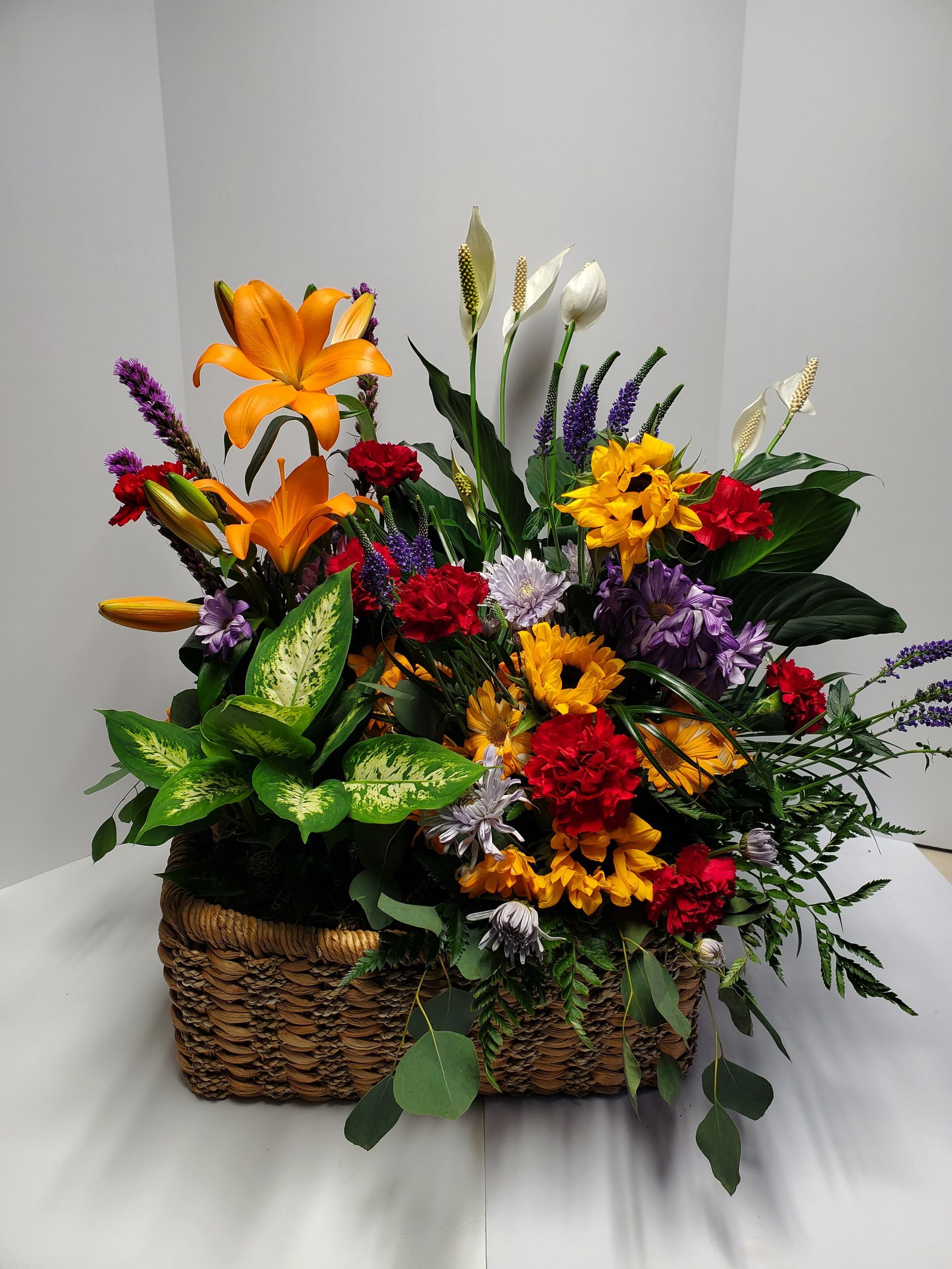 Colorful bouquet with yellow lilies, orange chrysanthemums, and purple flowers.