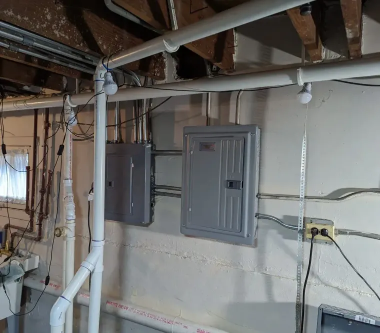 A technician wearing safety glasses works on solar inverter equipment mounted on a brick wall.