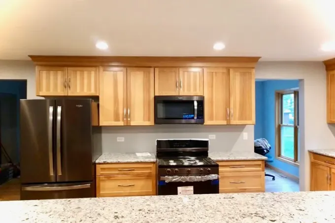 Modern kitchen with black appliances, light wood cabinets, and a granite countertop