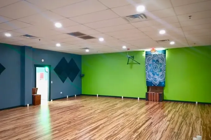 Empty room with wood floor, lime green walls, blue accent wall, and ceiling lights