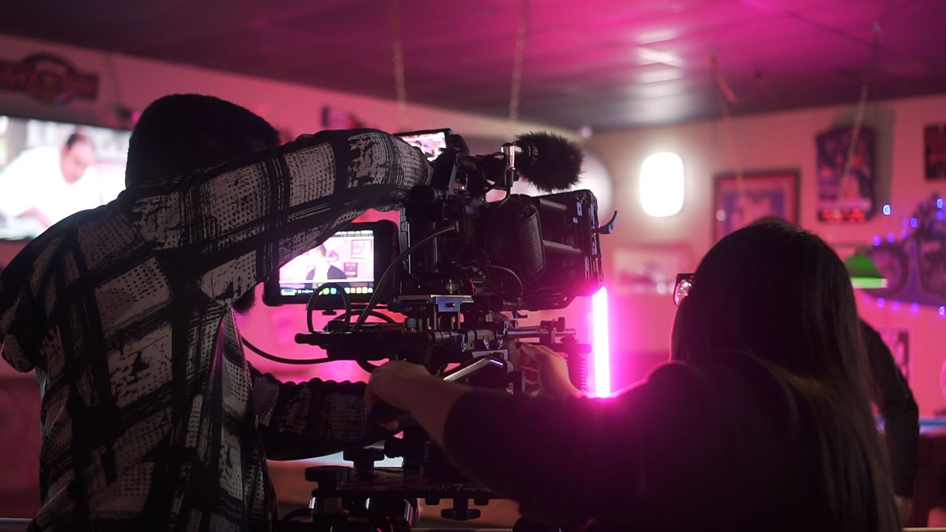 a man and a woman are standing in front of a camera in a dark room .