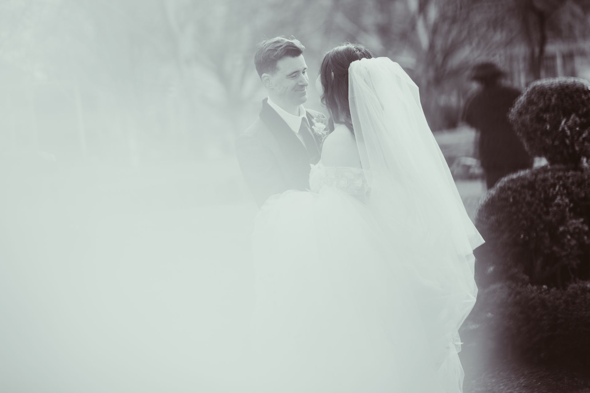 Bride and groom embracing in a soft, misty outdoor wedding scene