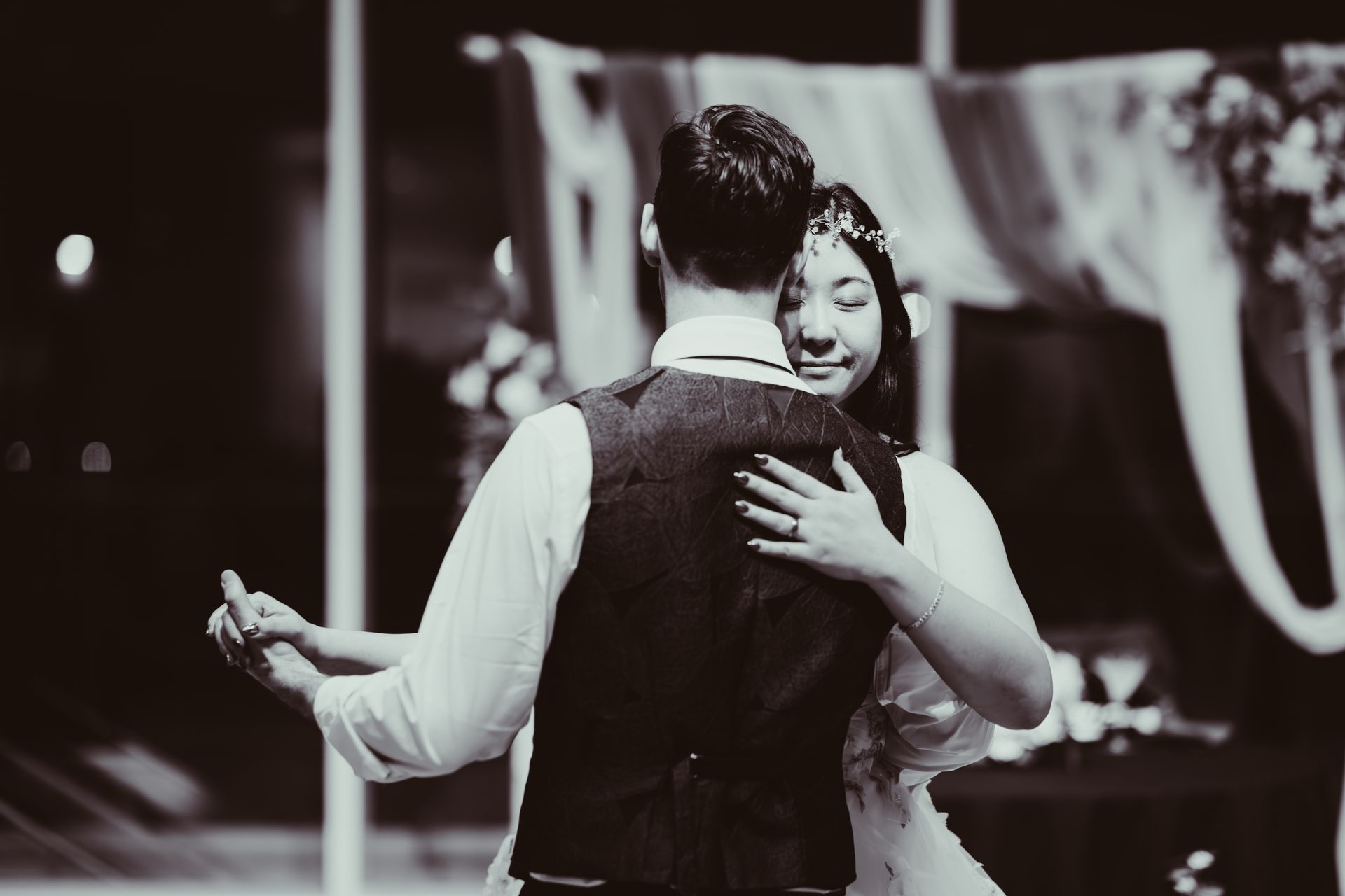 Two people dancing closely in a dimly lit venue, one with an arm around the other.