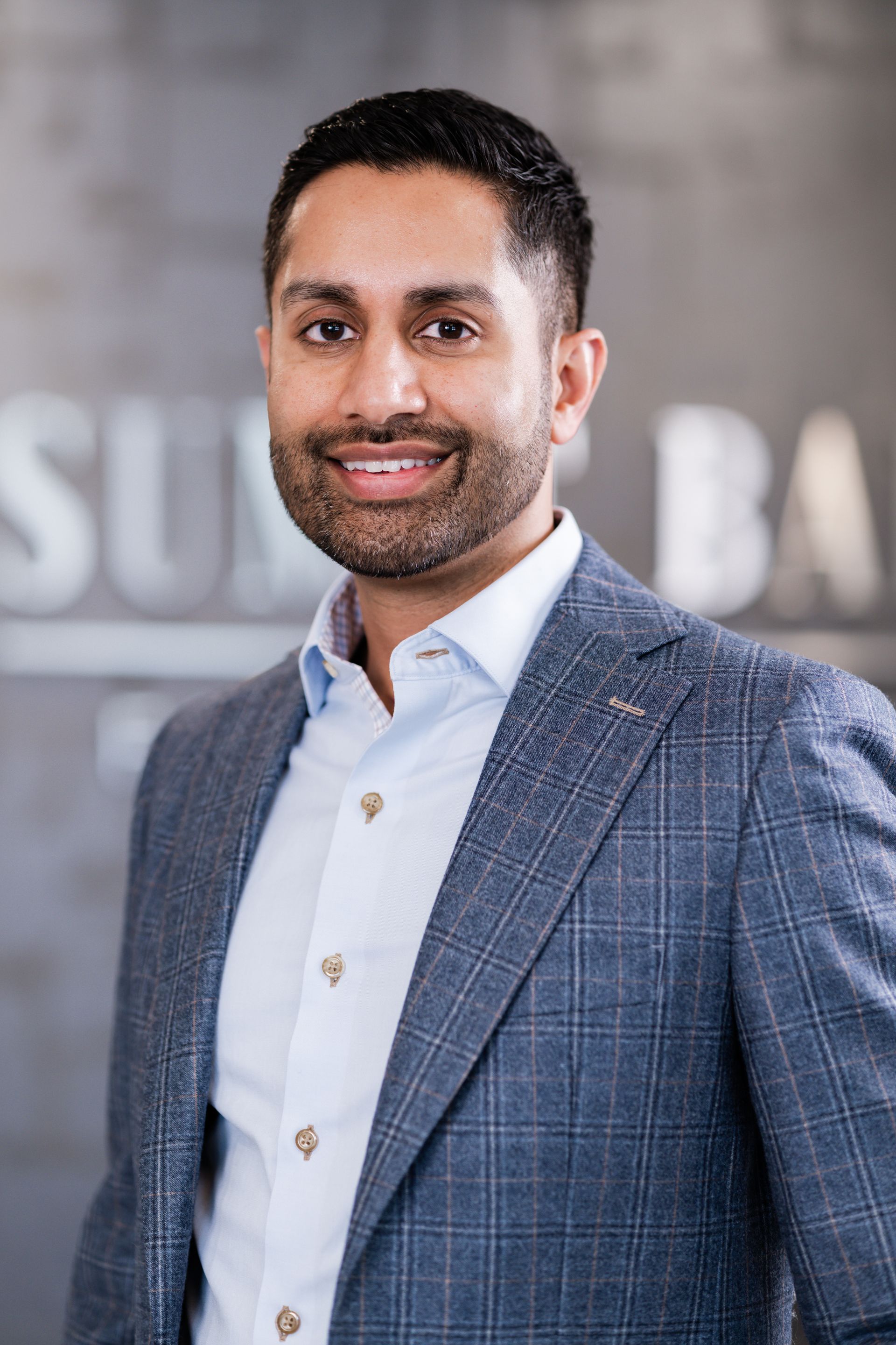 A man in a suit and white shirt is smiling for the camera.