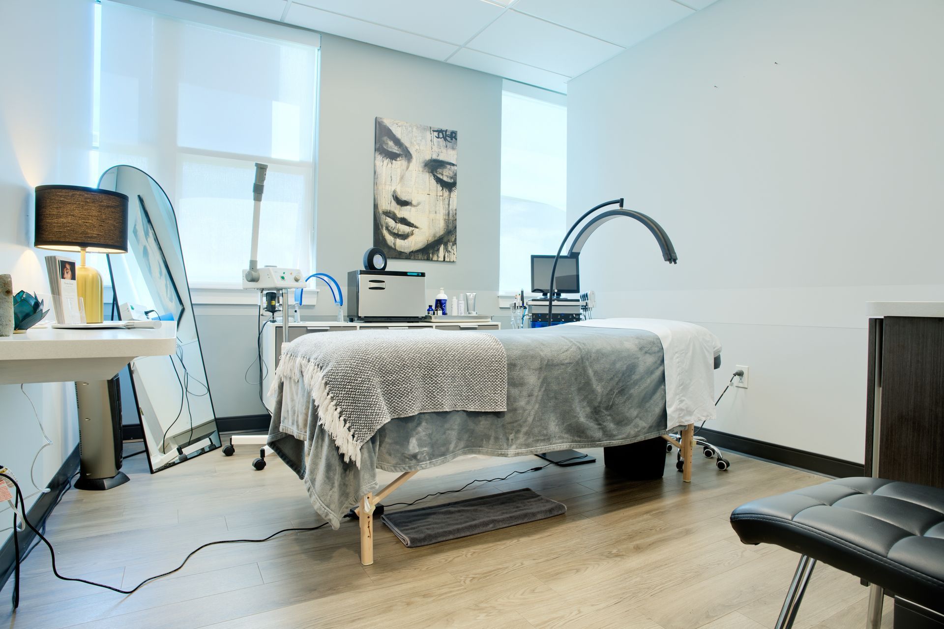 A massage table in a room with a picture of a woman on the wall.