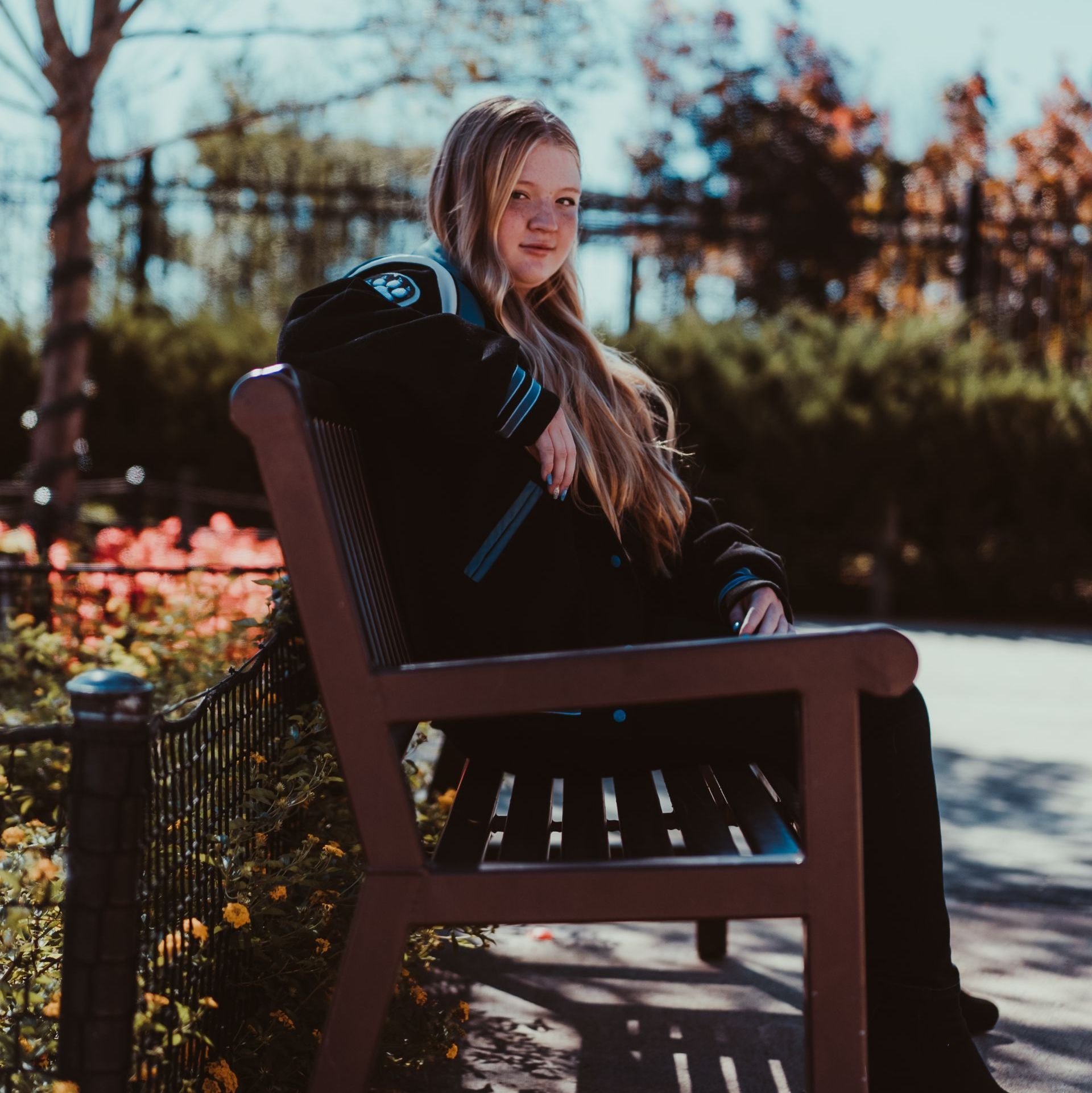 a girl is sitting on a bench with her arm resting on the arm rest