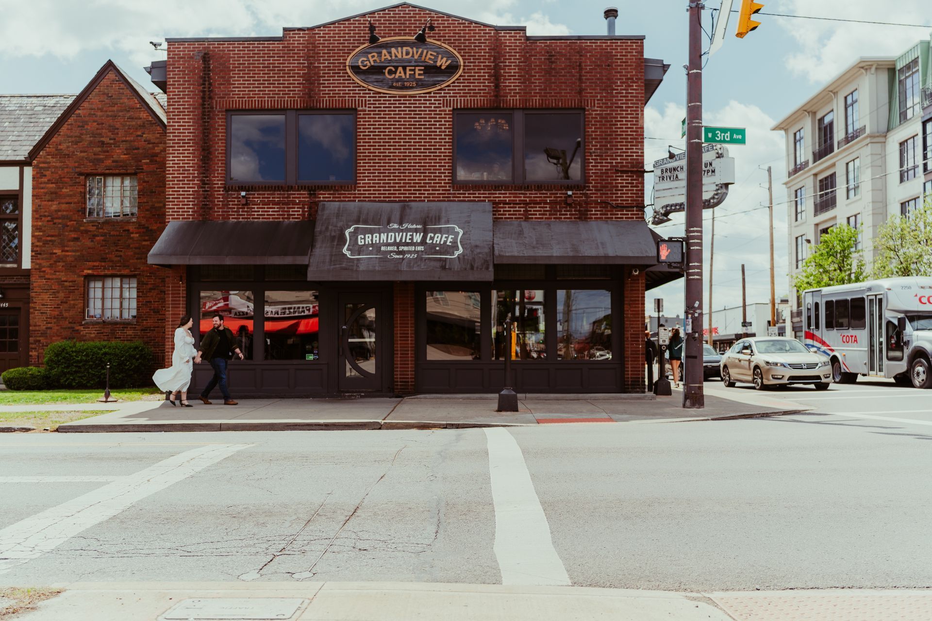 Brick storefront with large windows and a sign above a street corner intersection