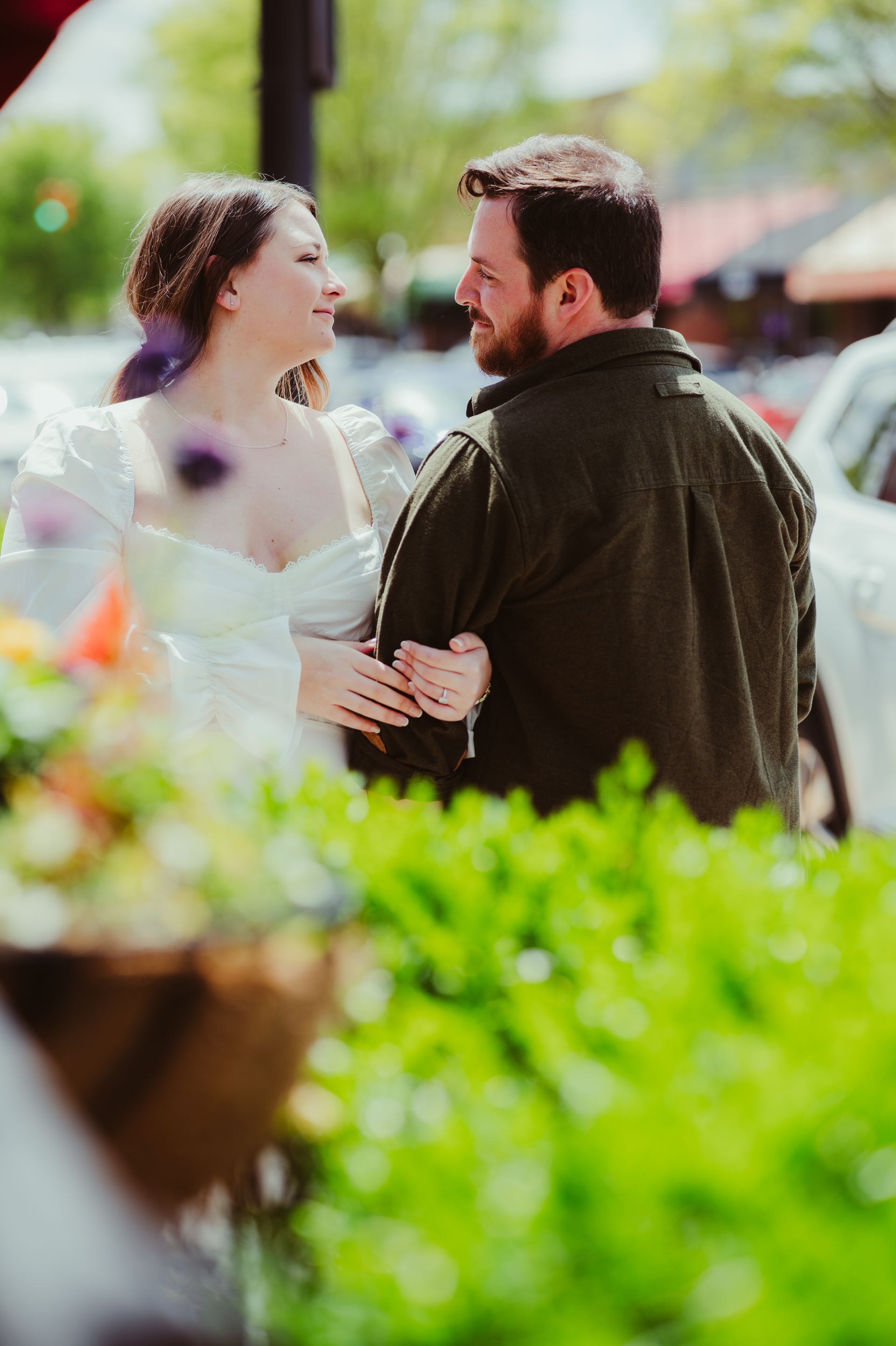 Two people smiling and talking outdoors, with bright flowers in the foreground.